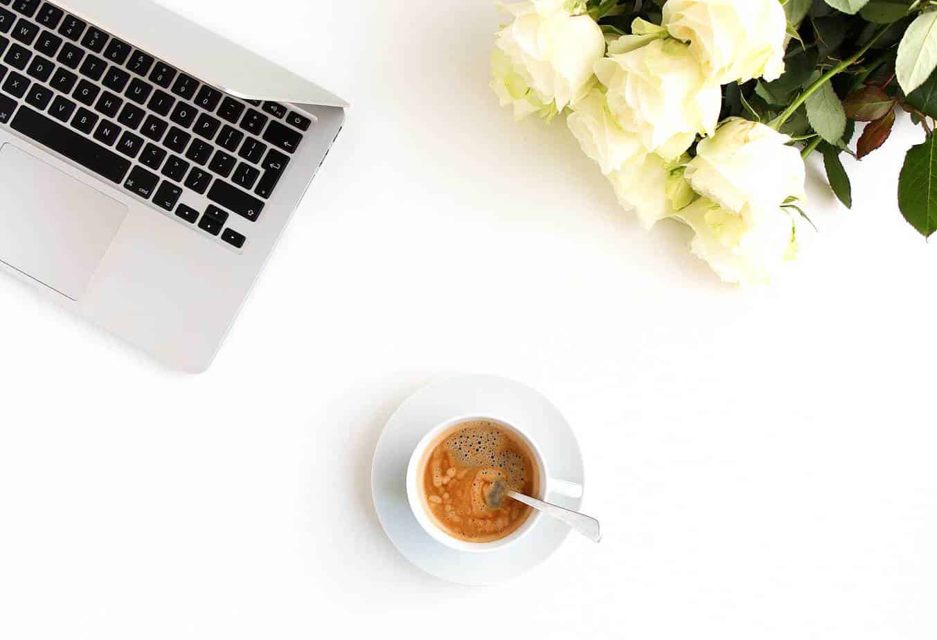 Roses, coffee, and laptop on a desk.