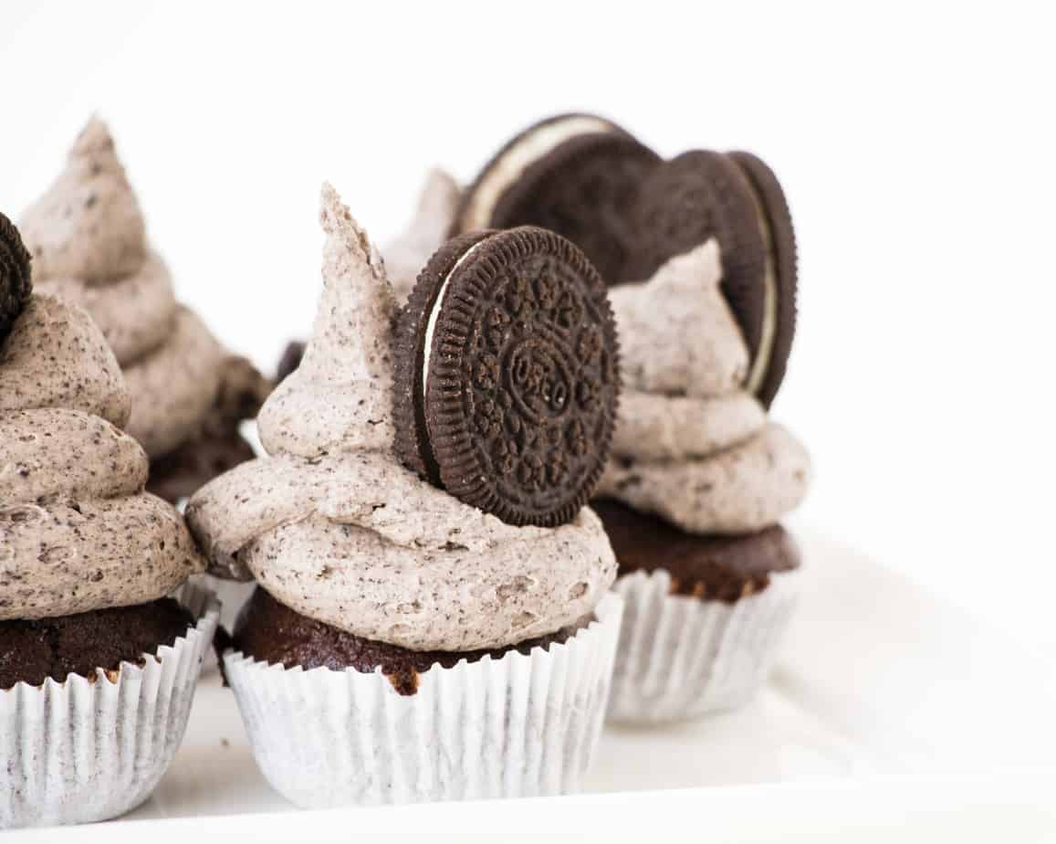Chocolate Oreo Cupcakes in white papers served with whole Oreo biscuits.
