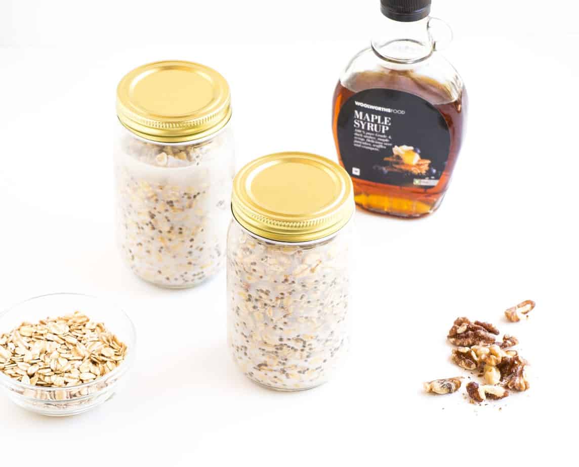 Protein powder Overnight Oats in two serving jars with maple syrup and oatmeal.