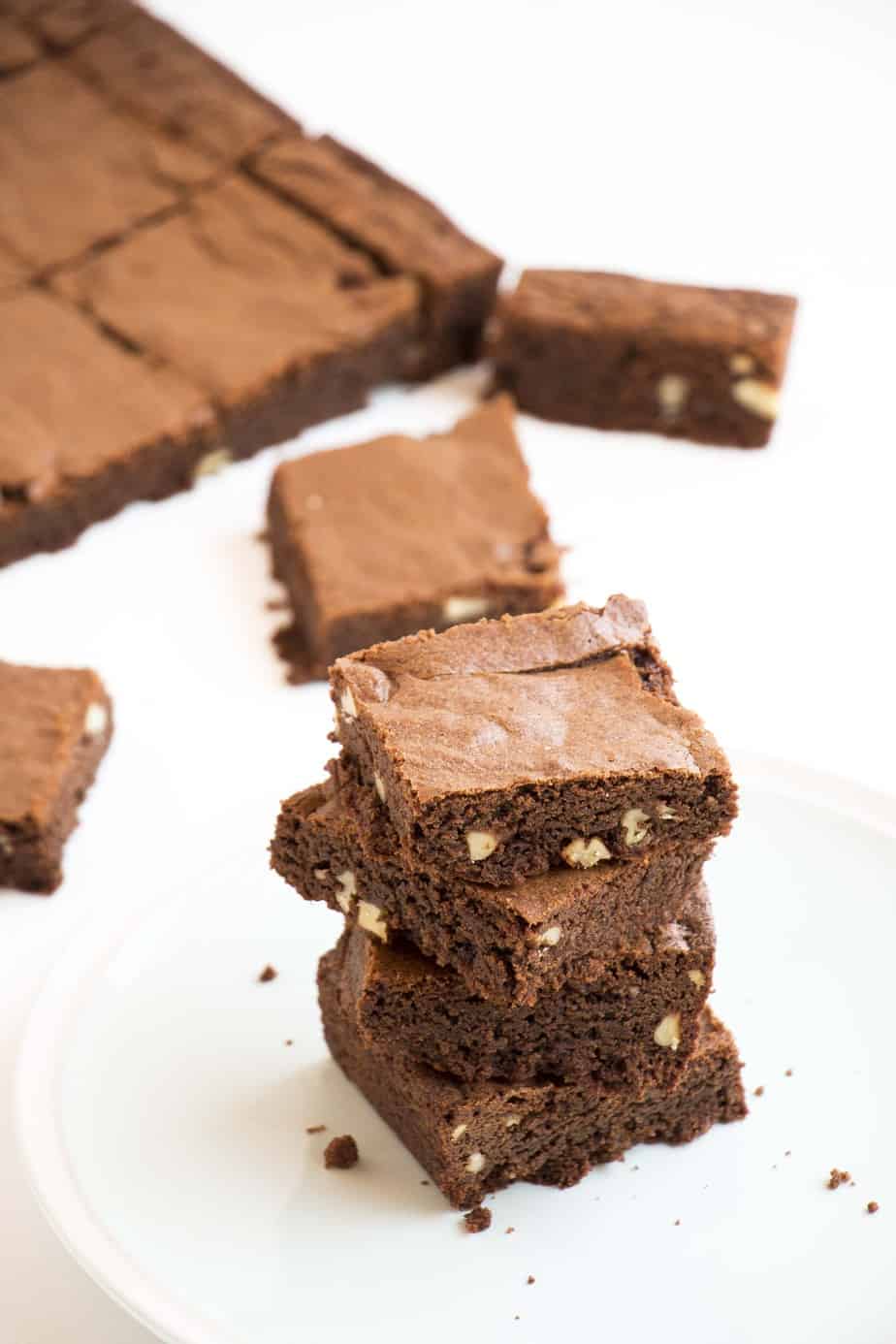 A stack of Chewy Chocolate & Pecan Brownies on a plate.