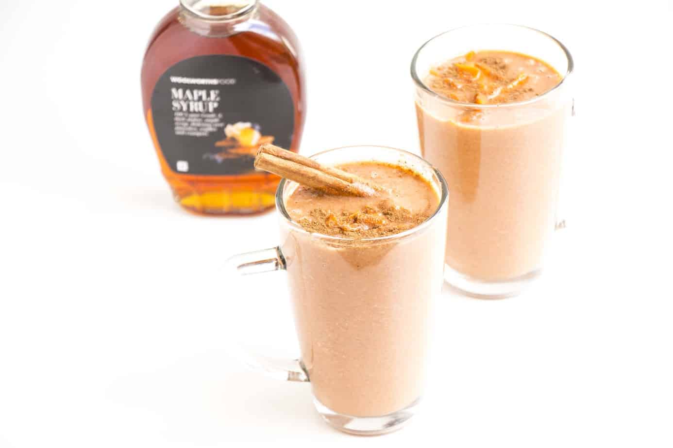 Two carrot banana smoothies in serving glasses garnished with cinnamon quills.