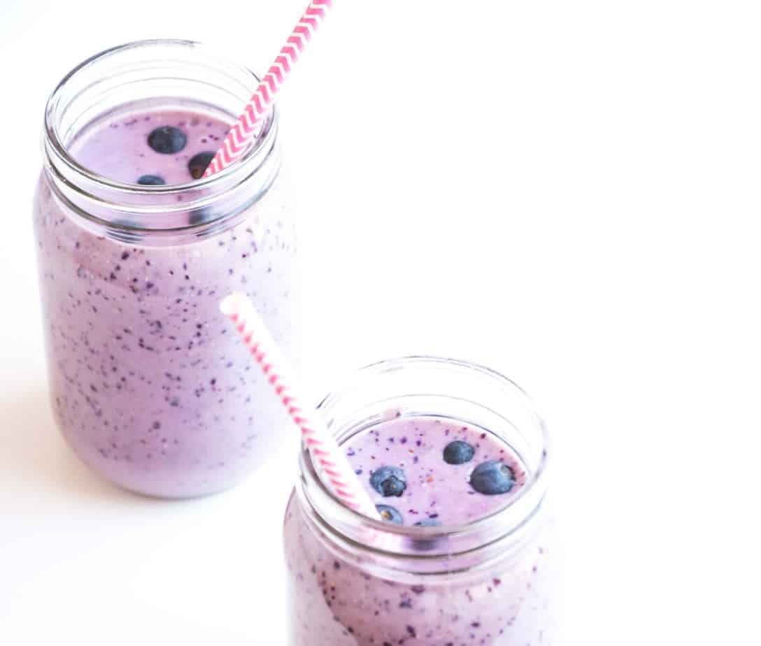Blueberry smoothies made with oat milk and garnished with fresh blueberries.
