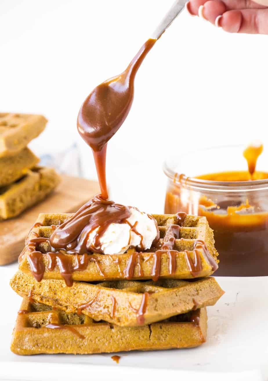 Healthy Pumpkin Waffles with Salted Caramel pouring over the top