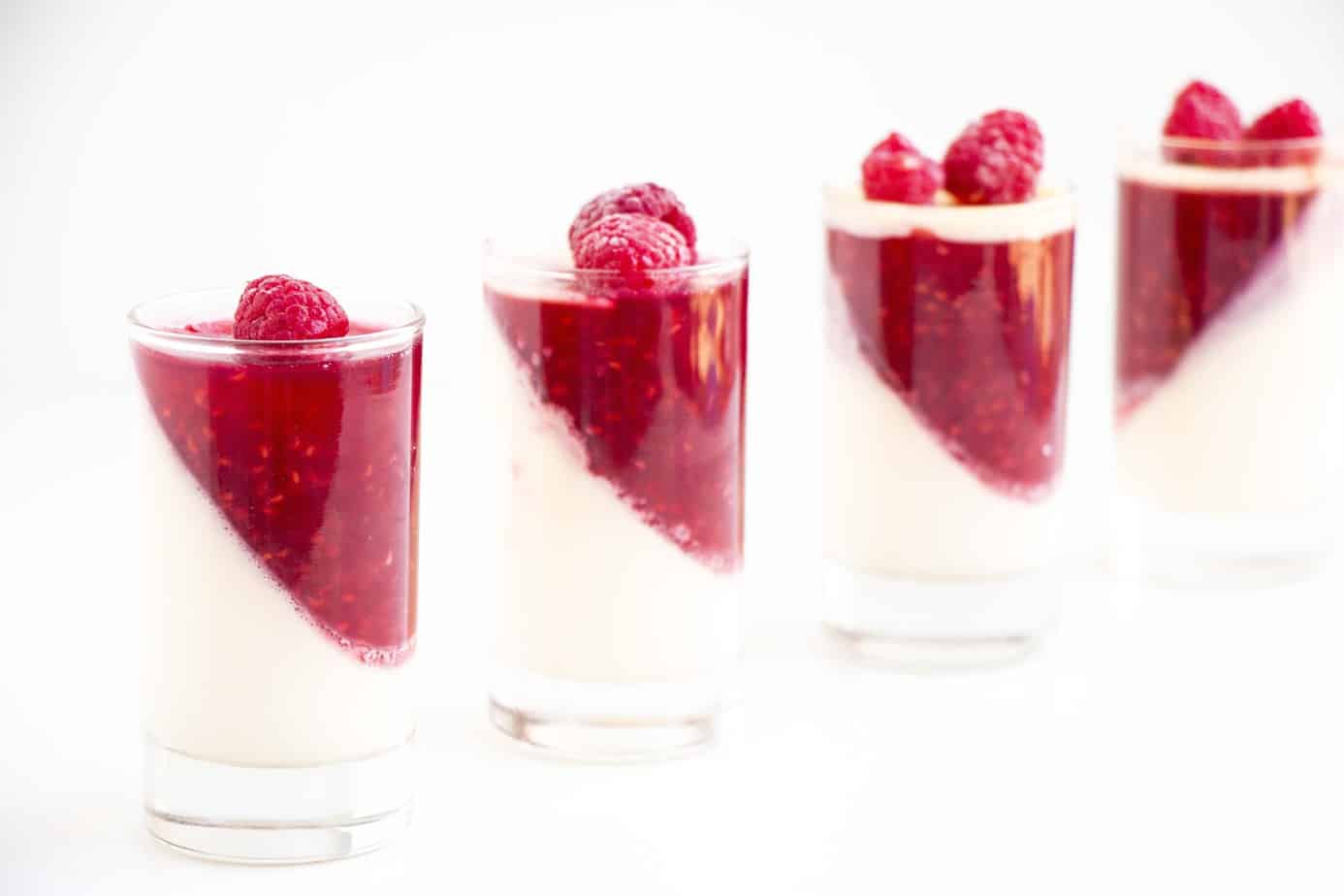 Vanilla Panna cottas topped with raspberry jelly and fresh raspberries.