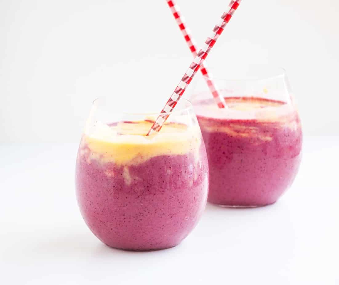 Mango Berry Smoothies in serving glasses with straws.