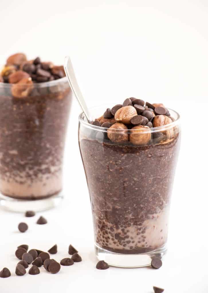 A glass of Chocolate Hazelnut Chia Pudding with nuts and chocolate chips.