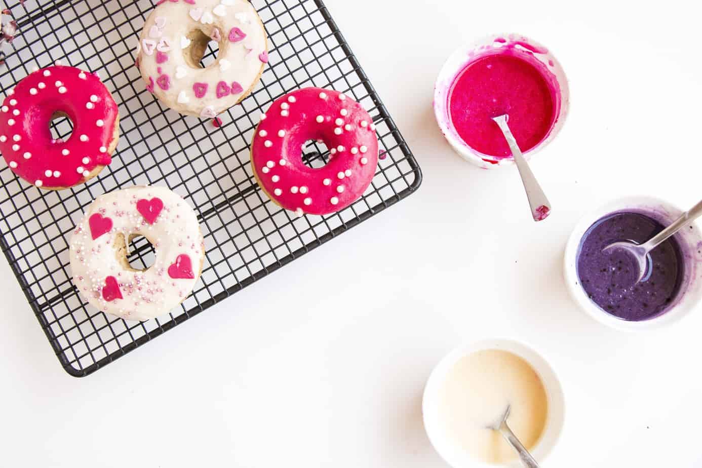 donuts on cooling rack with bowls of frosting.