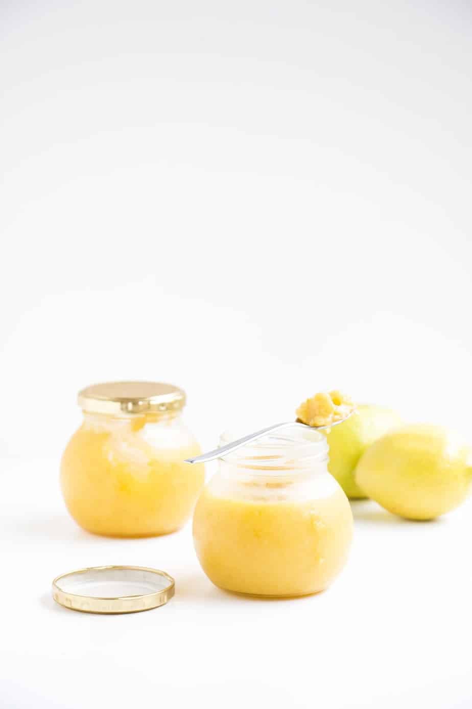 Glass jars filled with lemon curd with fresh lemons.