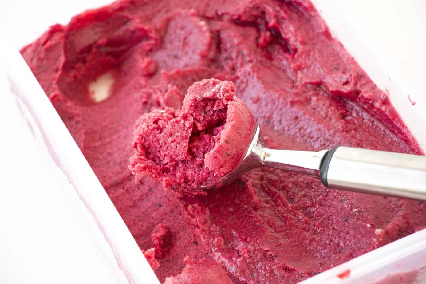 Mixed berry frozen yogurt with a metal scoop.