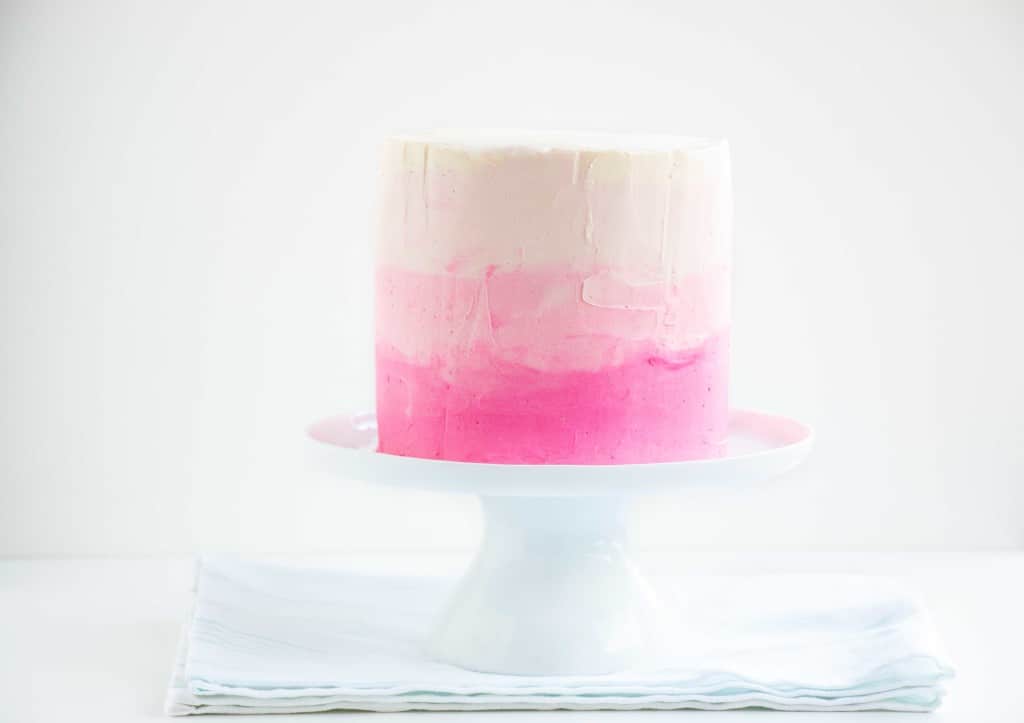 Pink ombre Cake on a white cake stand.