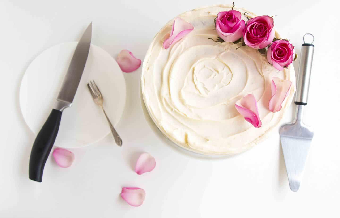 A frosted cake topped with fresh roses.