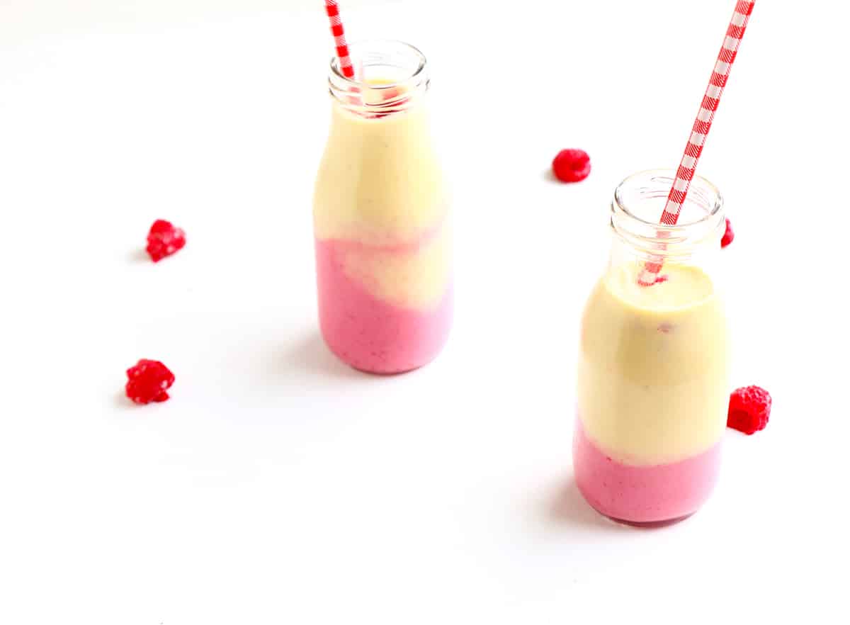 Two layered smoothies with fresh berries and straws.