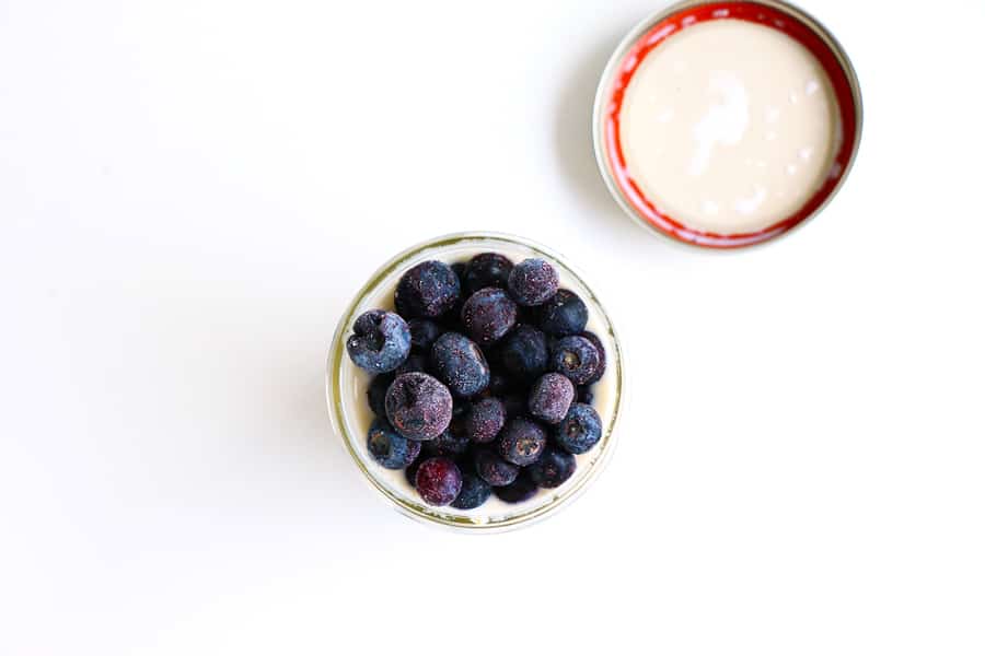 A bowl of blueberries and a bowl of almond milk.