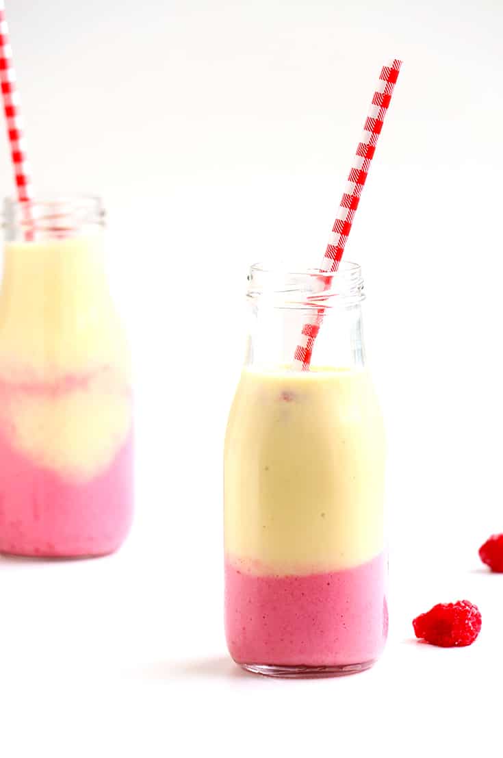 A smoothie in a glass serving jar with a straw.