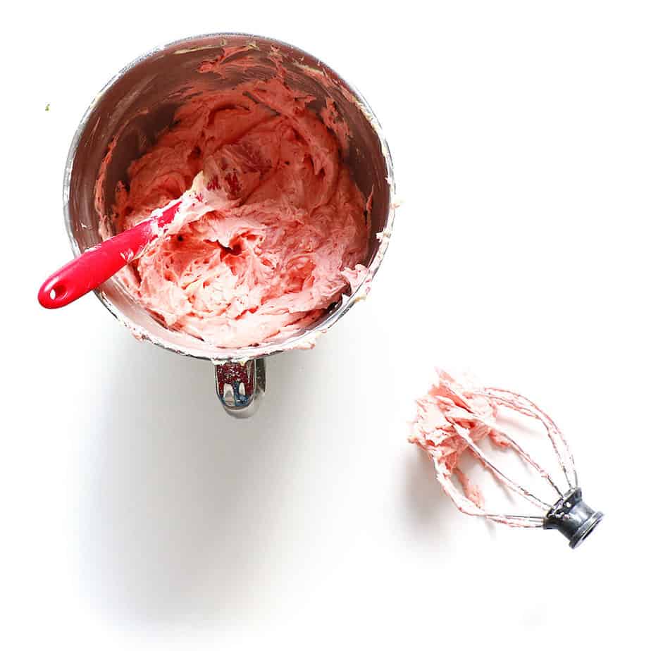 Raspberry frosting in a mixing bowl with a whisk.