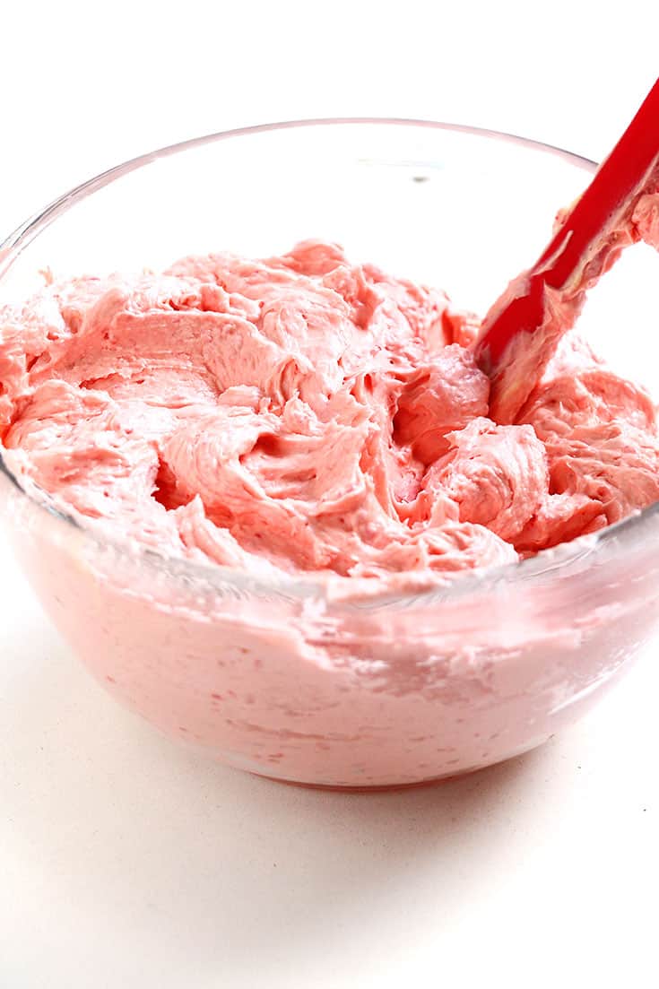 A glass bowl filled with pink raspberry buttercream.
