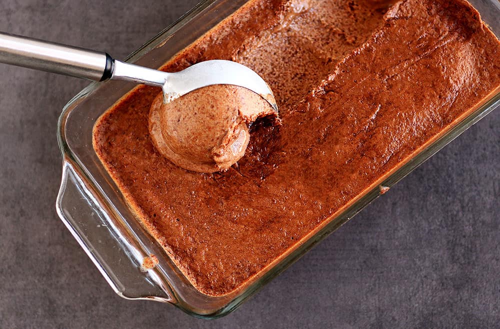 Ice cream being scooped out of a glass dish.