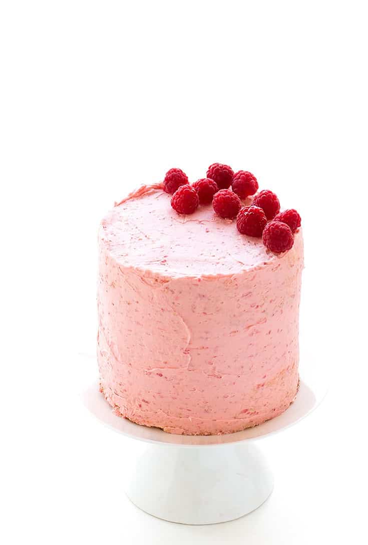 A pink layered cake on white cake stand.