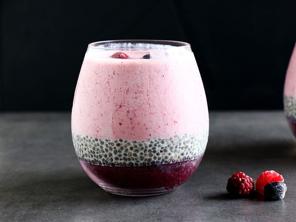 A healthy Layered Berry Smoothie Chia Pudding on a black background.