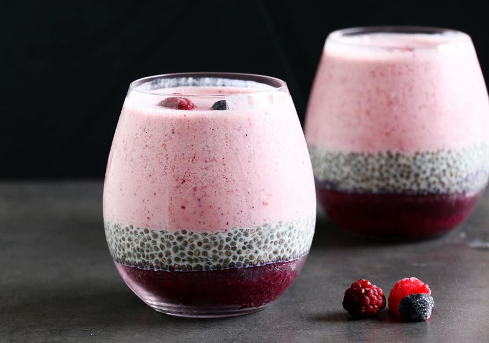 A healthy Layered Berry Smoothie Chia Pudding on a black background.