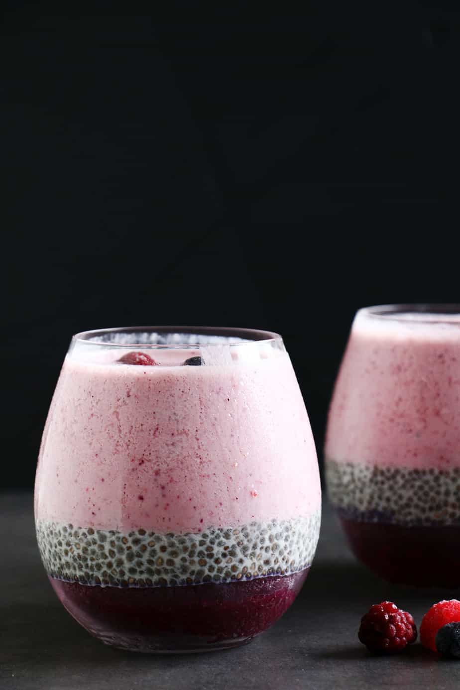 A healthy Layered Berry Smoothie Chia Pudding on a black background.