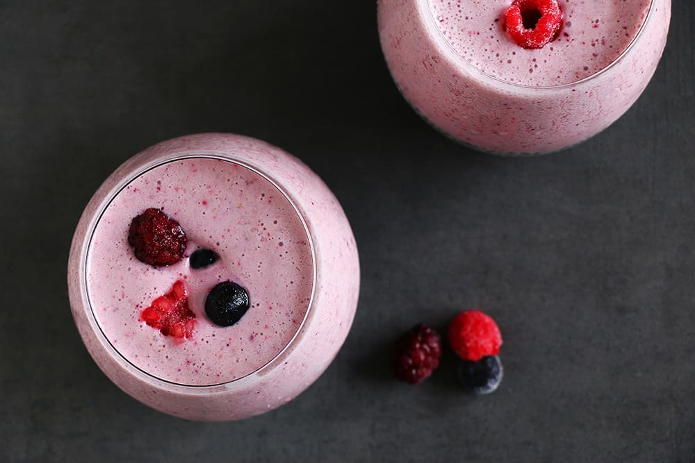 Two smoothies with berries on a gray background.
