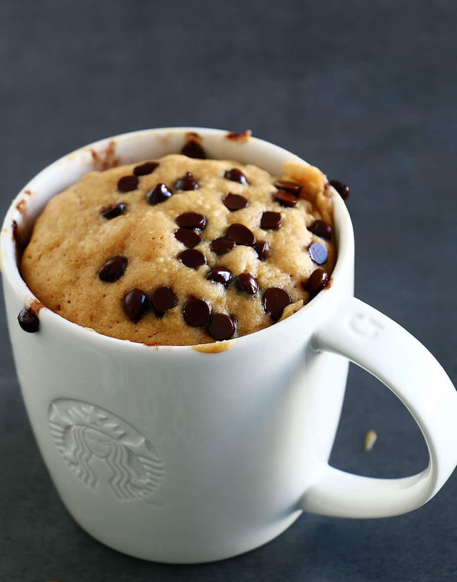 A healthy peanut butter cake in a white mug with chocolate chips.