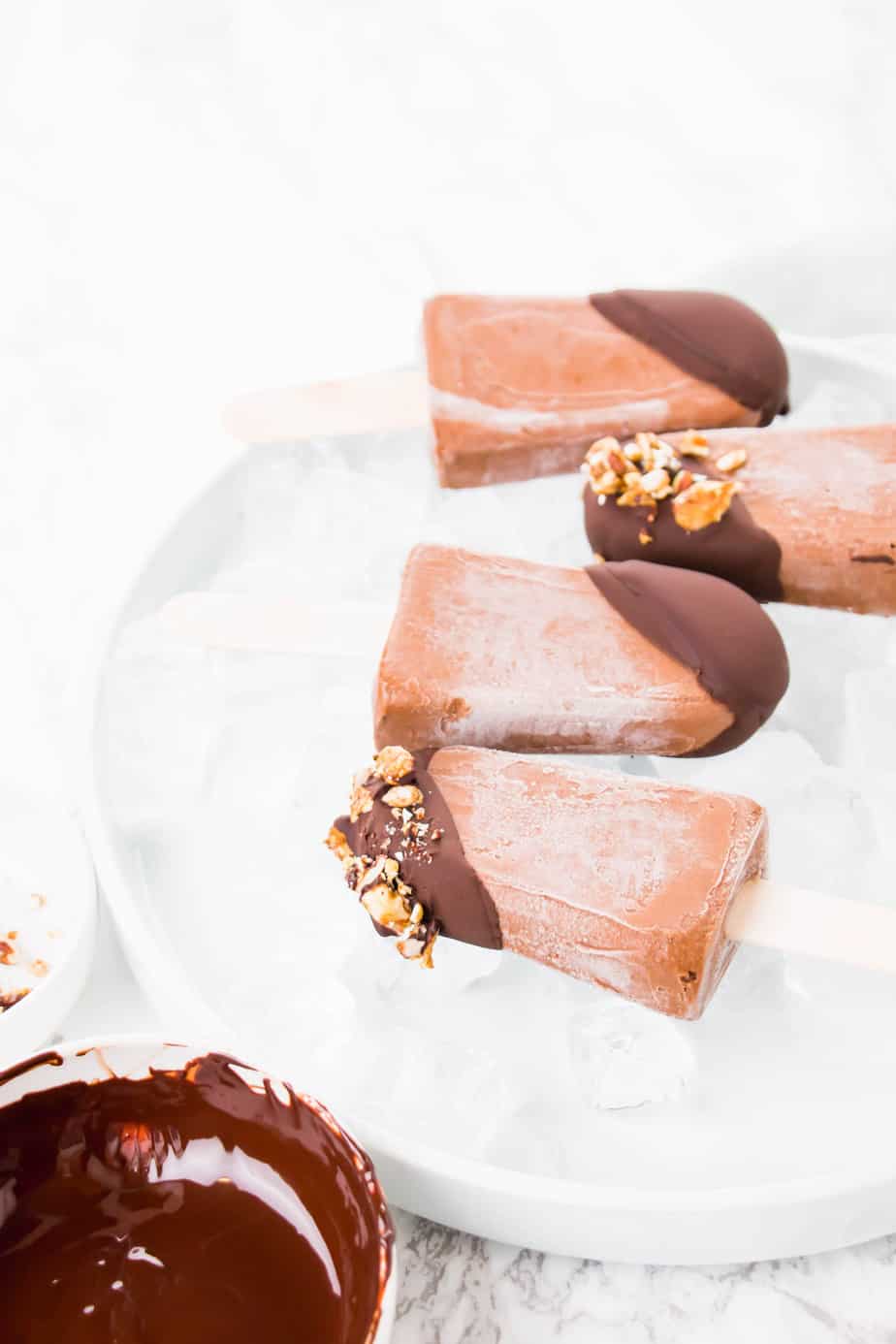 These Vegan Chocolate Protein Popsicles make the best on the go breakfast or the ultimate summer dessert. Made with vegan protein, coconut milk and topped off with dark chocolate ganache and crunchy granola.