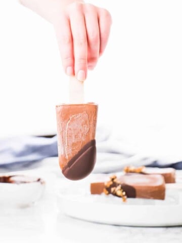 These Vegan Chocolate Protein Popsicles make the best on the go breakfast or the ultimate summer dessert. Made with vegan protein, coconut milk and topped off with dark chocolate ganache and crunchy granola.