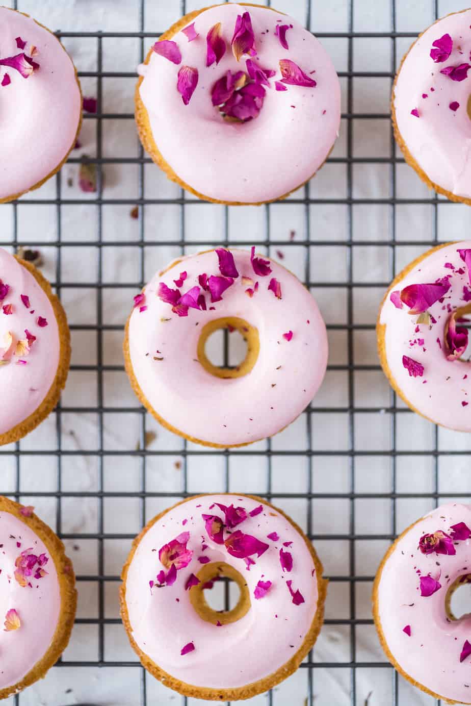 Pink glazed donuts on a cooling wrack.