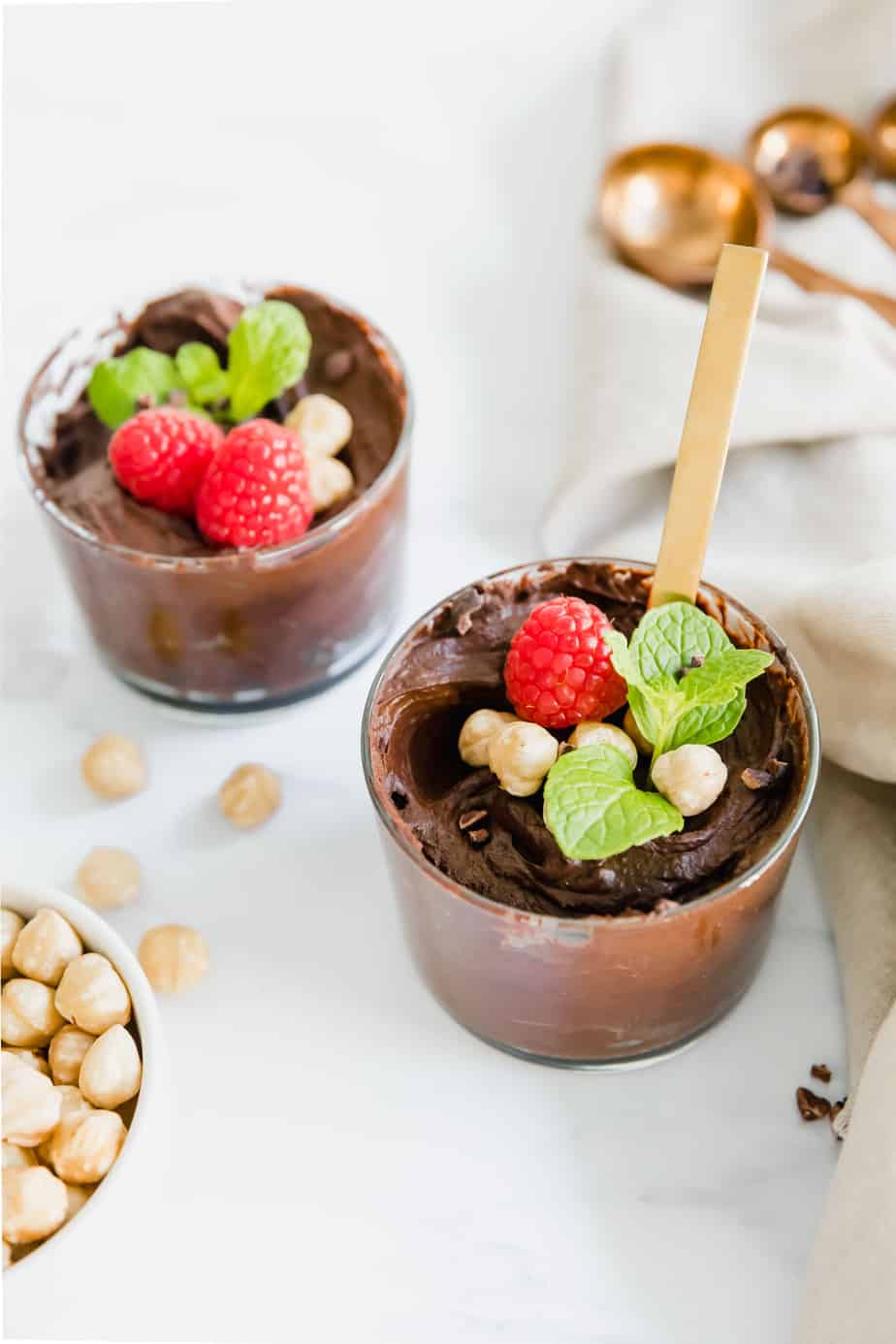 Chocolate mousse in glass serving dishes with berries and fresh mint.