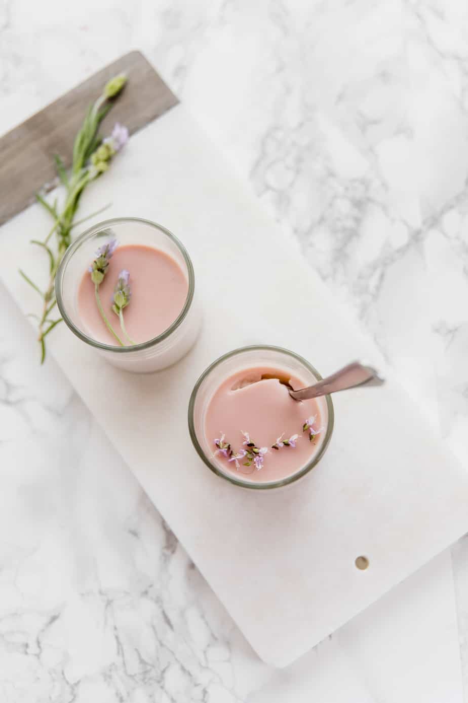 Two lavender panna cottas in serving glasses with lavender flowers.