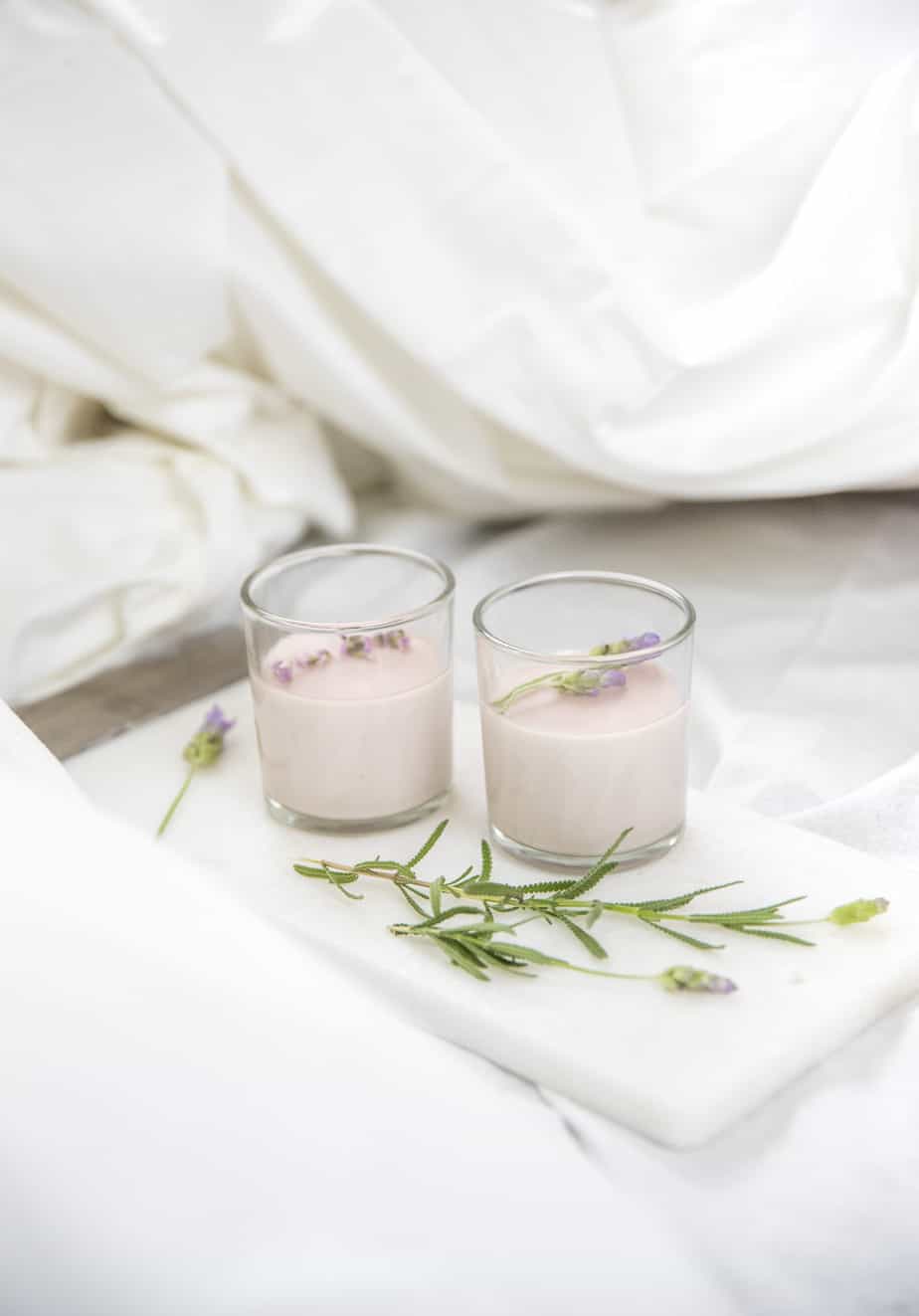 Two lavender panna cottas in serving glasses with lavender flowers.