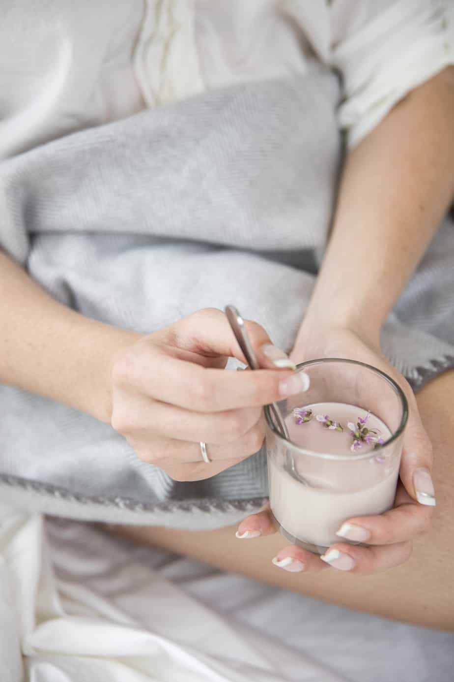 A person eating a panna cotta in a glass serving dish.