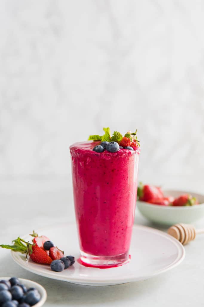 Strawberry Beetroot Detox Smoothie in a glass on a white plate.