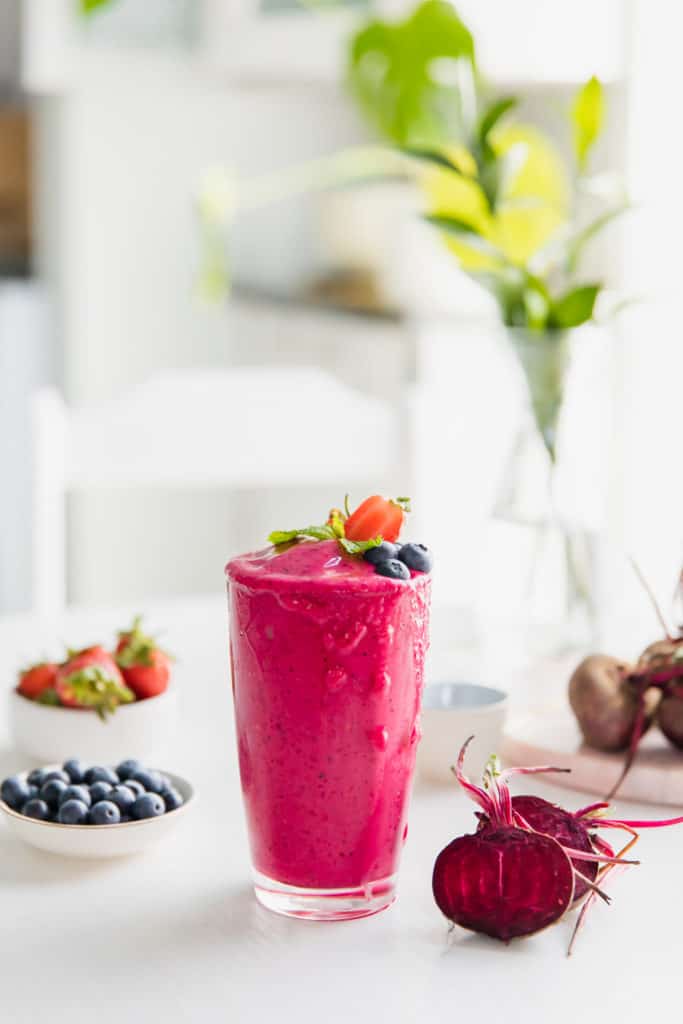 A pink smoothie with ingredients.