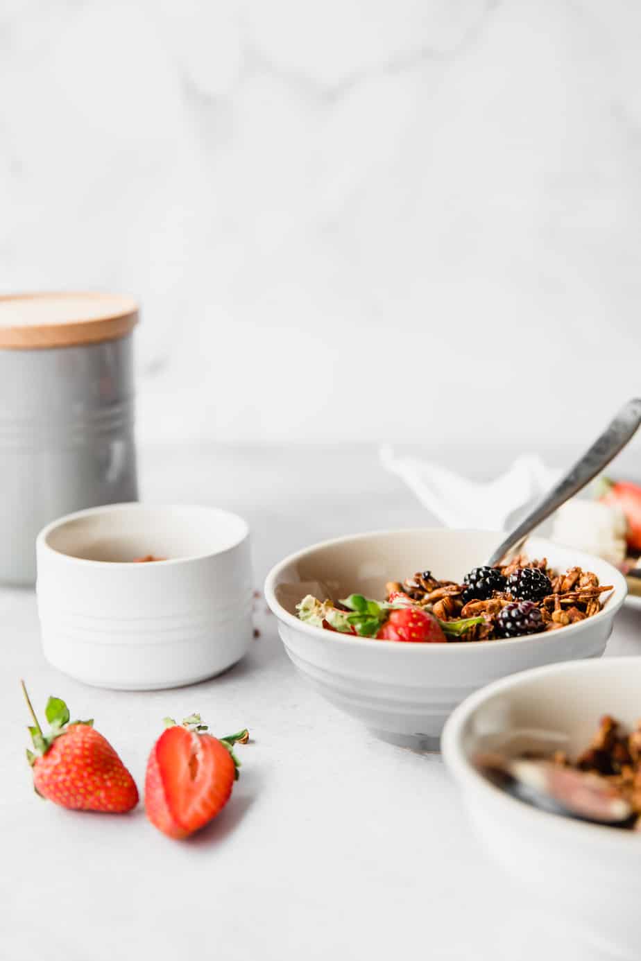 A white bowl filled with granola and fresh fruit.