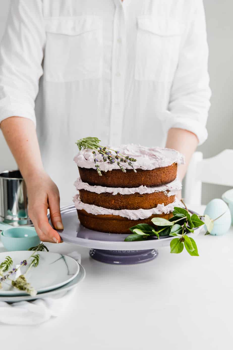 A Lavender and Earl Grey Cake on a purple cake stand with fresh lavender.