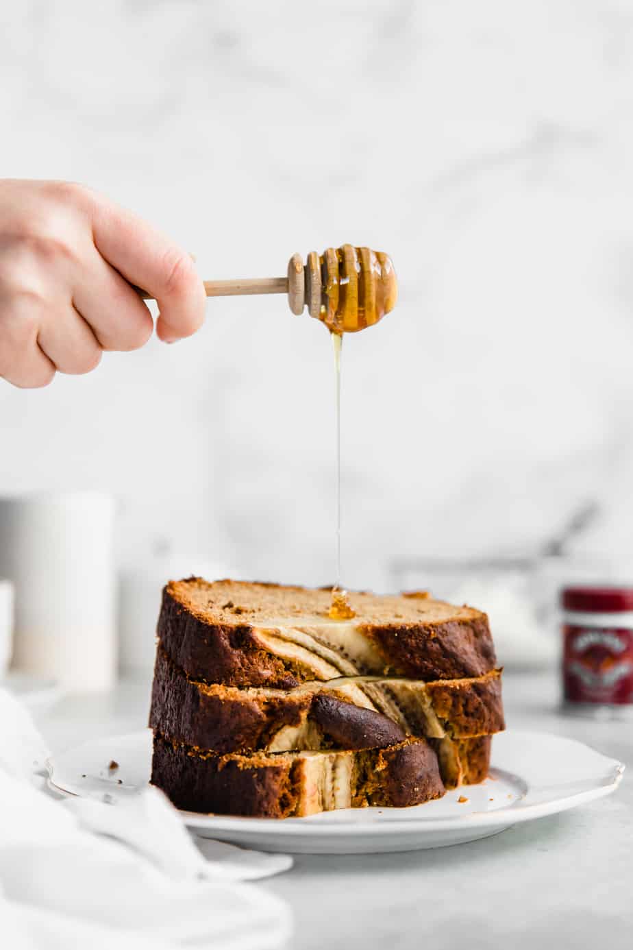 Honey dripping over a stack of sliced fluffy banana bread.