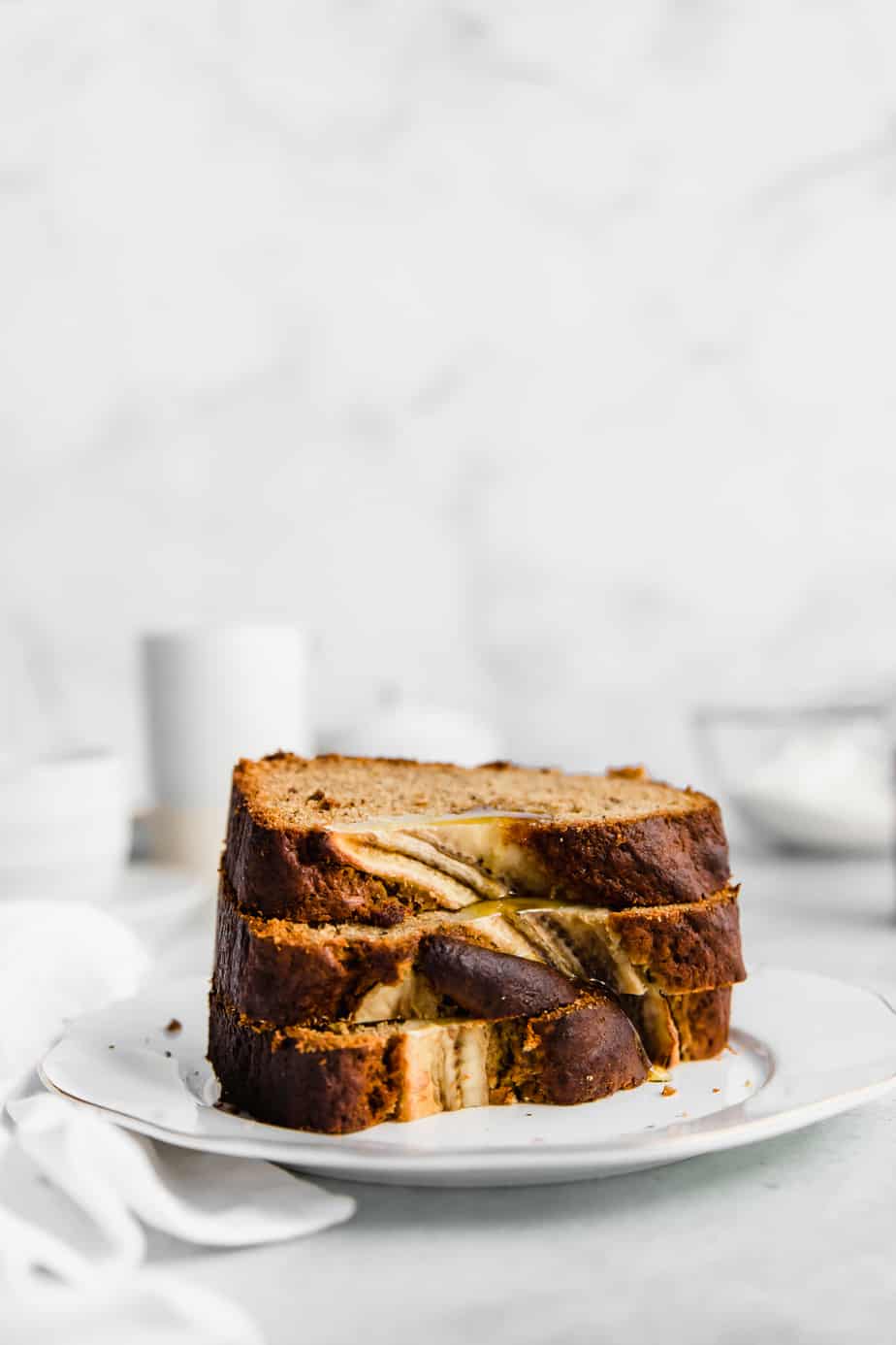 Thick slices of banana bread stacked on a white plate.
