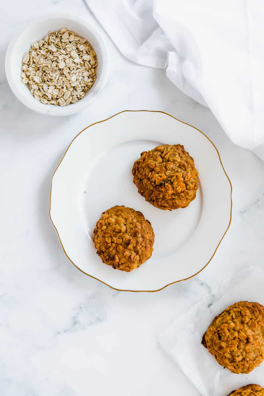 Two carrot oatmeal cookies sitting on a white plate.