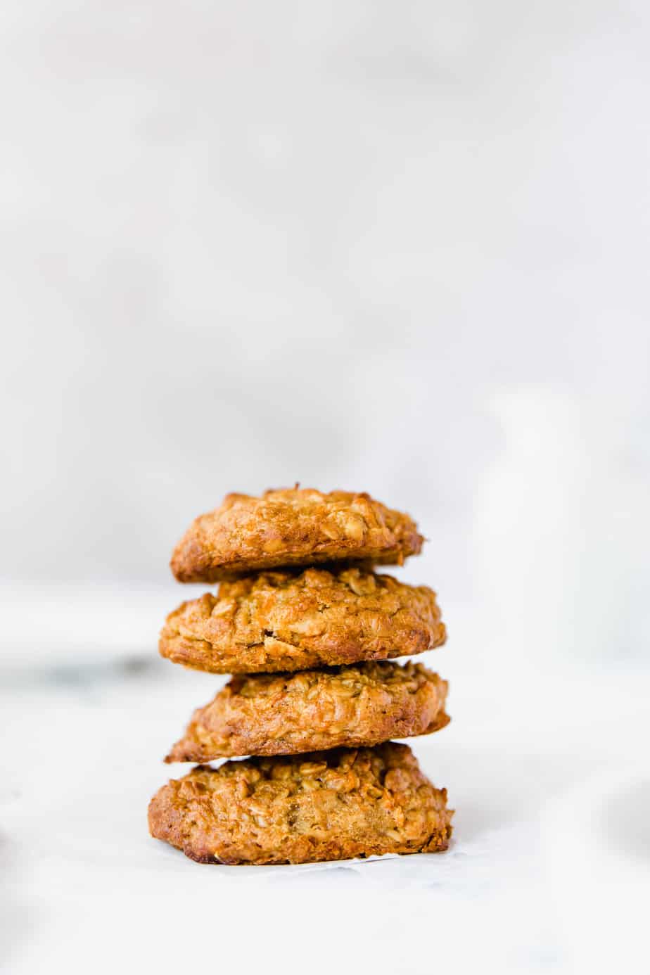 A stack of four carrot oatmeal cookies sitting on a white table. 