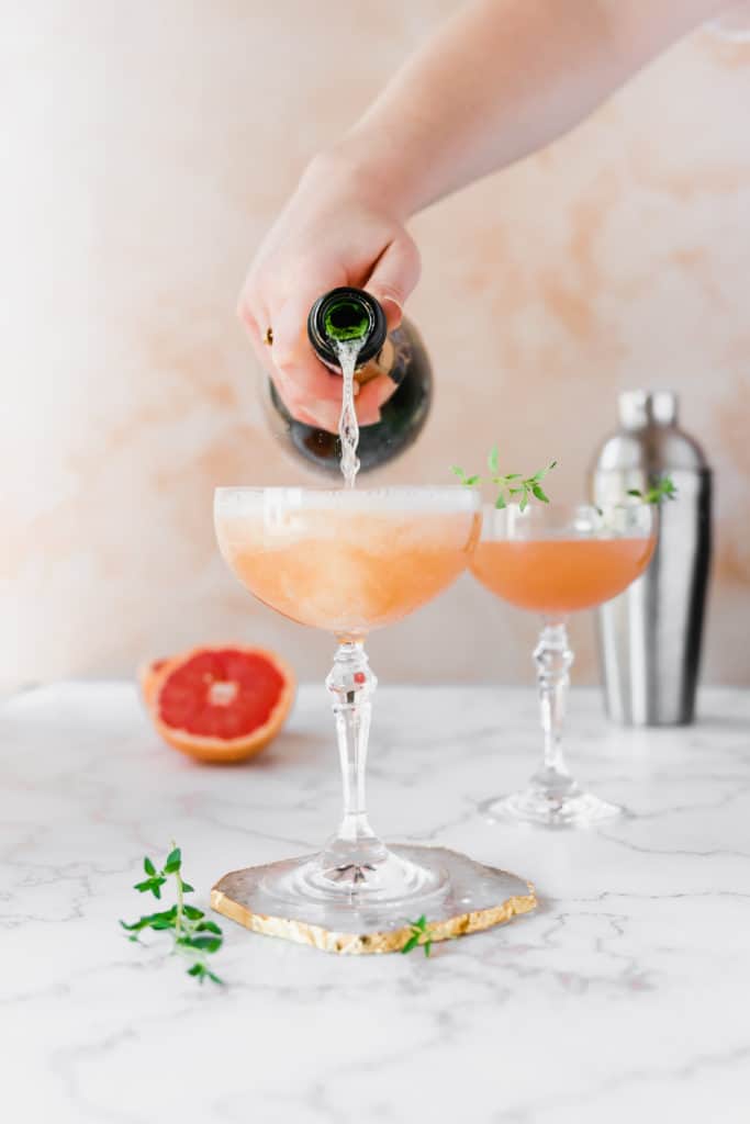 Two cocktail glasses garnished with fresh thyme sprigs.