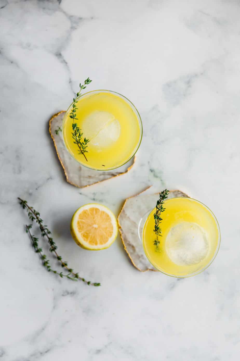 Two pineapple gin & ginger beer cocktails with ice and fresh thyme