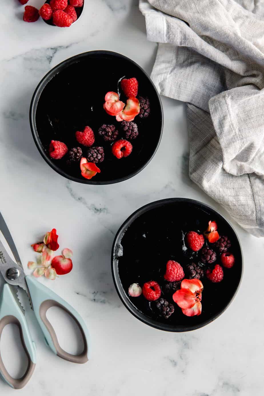 Two black activated charcoal smoothie bowls topped with berries.