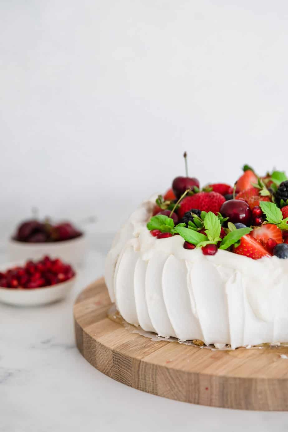 A pavlova topped with mixed berries and fresh mint