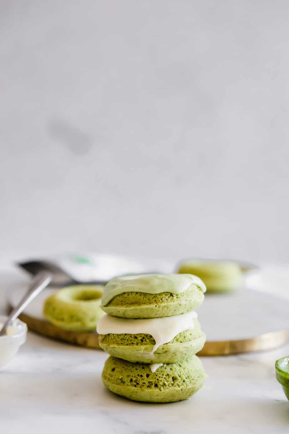 A stack of green matcha donuts with a grey background.