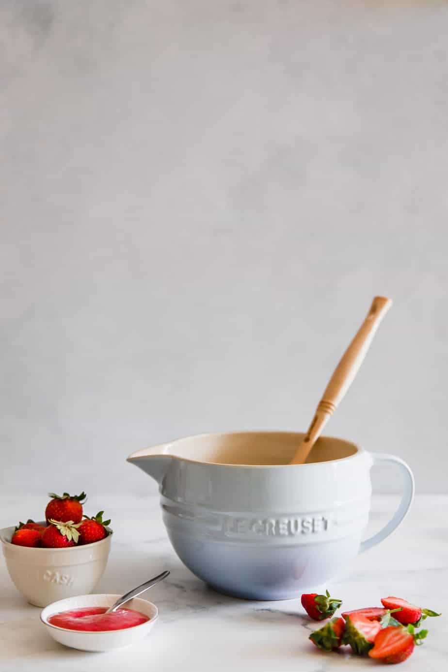 A mixing bowl with fresh strawberries and strawberry puree.