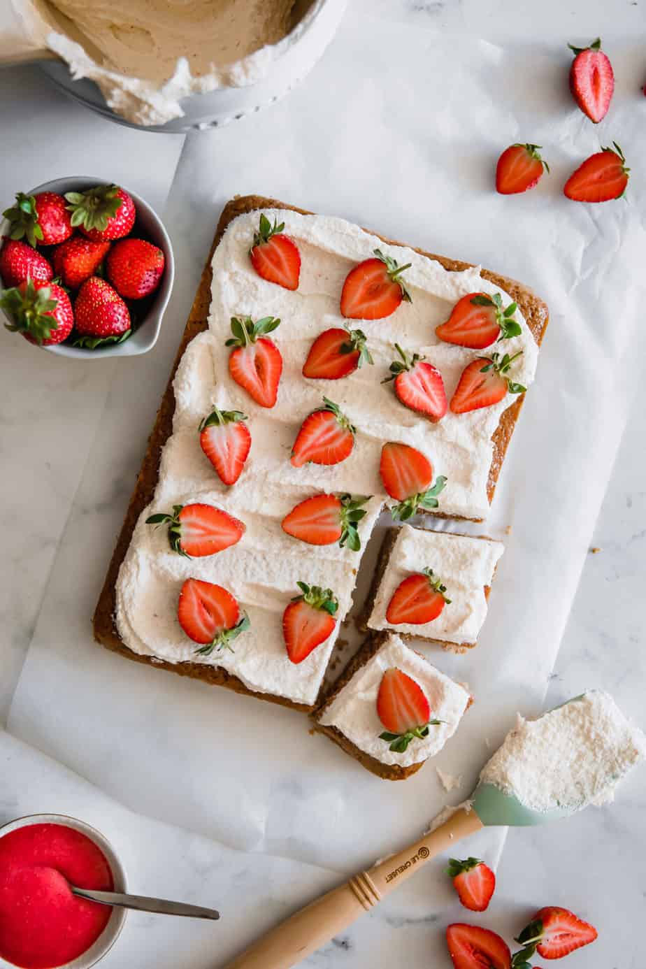 A sheet cake topped with fresh strawberries and buttercream frosting.