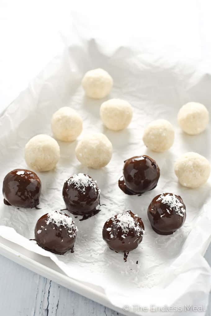 A tray with baking paper containing chocolate covered healthy bliss balls.
